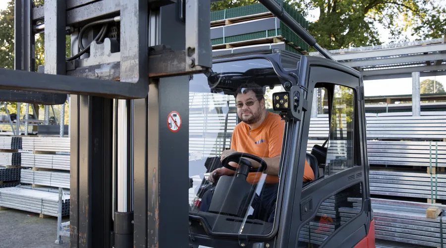 Jongen zit op de vorheftruck en kijkt door de voorruit naar de camera