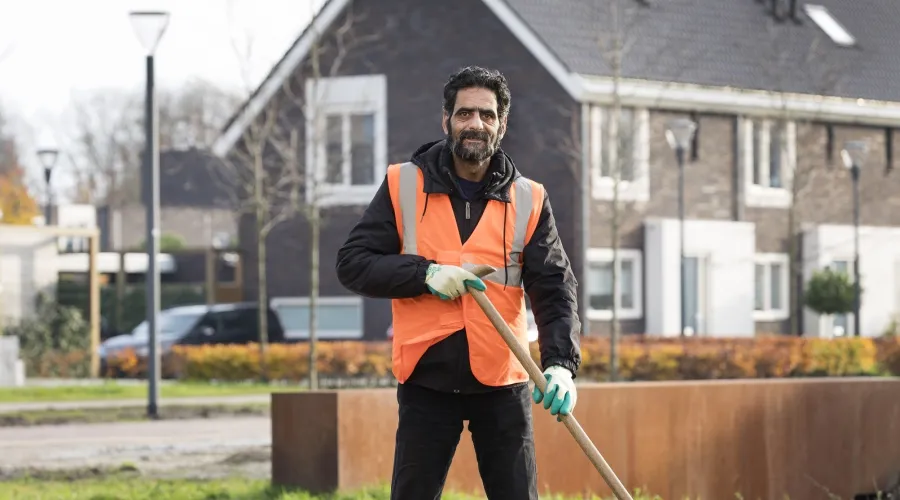 Een nieuwe Nederlander werkt in het groen en heeft een schoffel in zijn handen