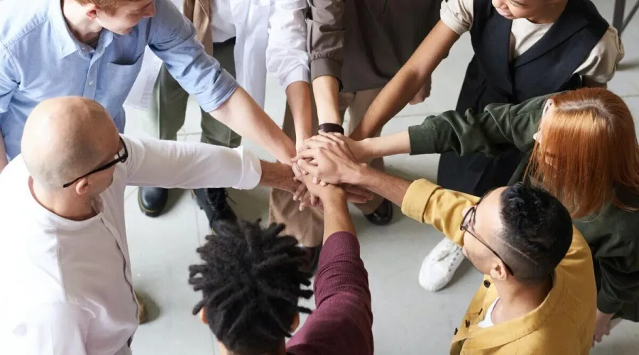 groep mensen in een cirkel die hun handen op elkaar leggen