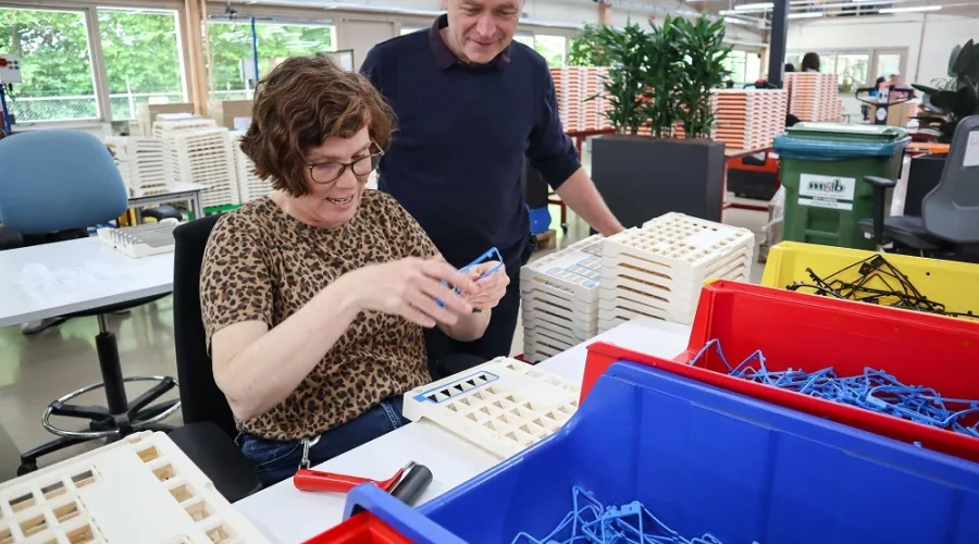 medewerker werkt in de productiehal terwijl werkbegeleider toekijkt