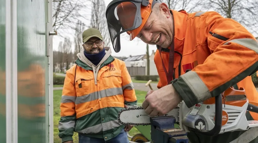 Twee mensen in het groen maken een snoeizaag schoon