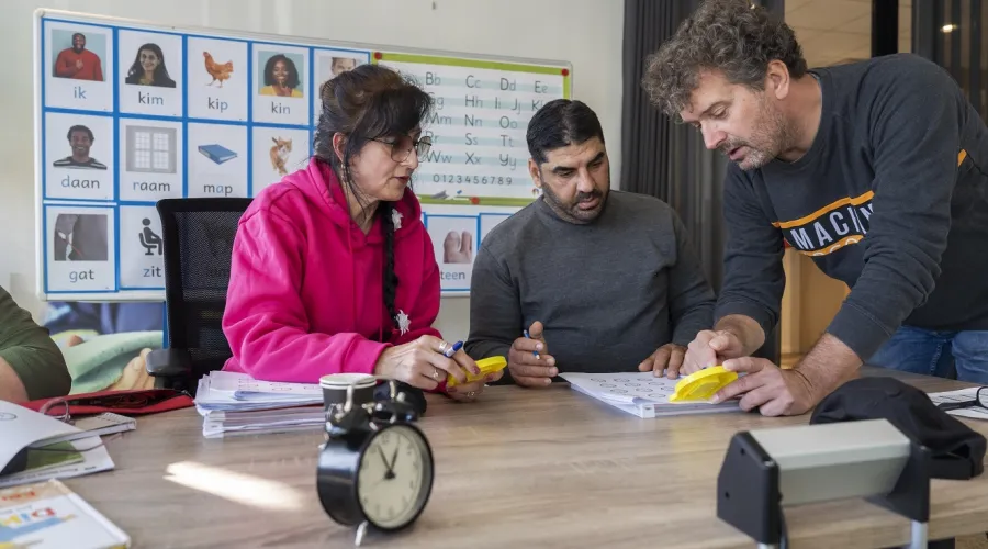 Inburgeraars krijgen Nederlandse les met het thema klok kijken