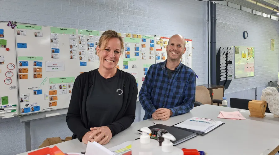 Twee werkbegeleiders staan bij een werktafel in het textielsorteercentrum